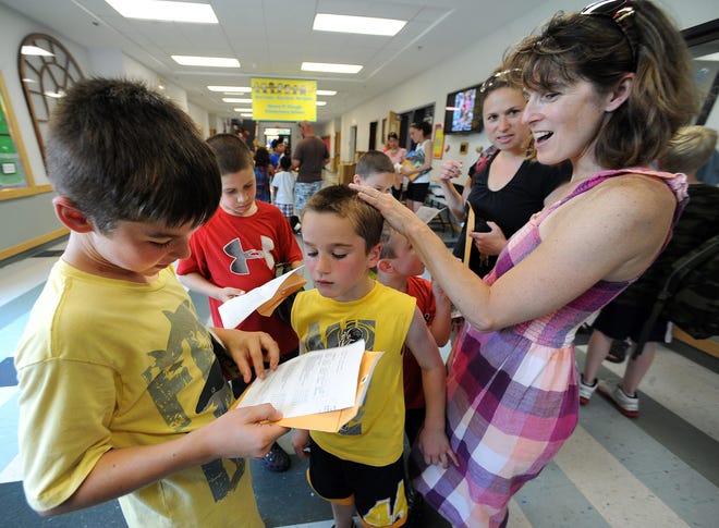 Fourth-grader Cameron Duncan looks over his final report card with his brother, Colby, and mother, Diane, on the last day of school at Mendon's Clough Elementary School.