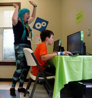 In this Wednesday, June 19, 2013 photo, instructor Melissa Andrews, left, cheers on camper Roger McKee, 9, for finishing a video game while at an iD Tech Camp at the Emory University campus, in Atlanta. So-called coding camps for kids are becoming more popular amid a growing effort to expand access to computer programming and inspire more youths to seek computer science degrees and later careers in technology. (AP Photo/Jaime Henry-White)