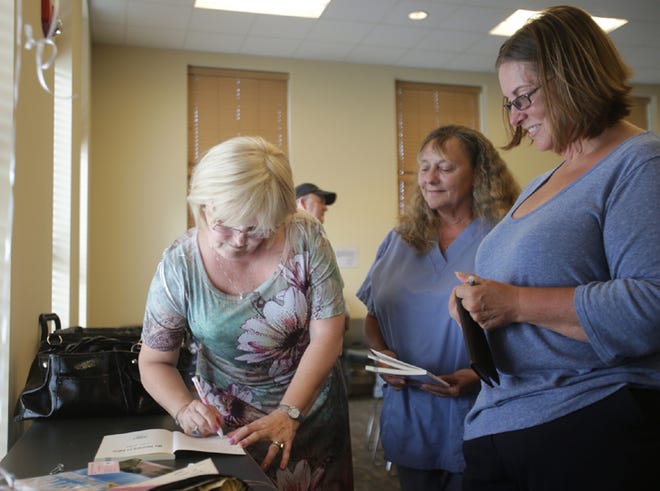 Lisa Pelt autographs copies of her book "My Journey to Eden" during a book signing at the Bay County Public Library in Panama City on Thursday.