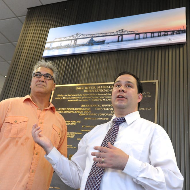 Mayor Will Flanagan talks about Michael O'Neil's photo, seen behind them at Government Center, at its unveiling Monday.