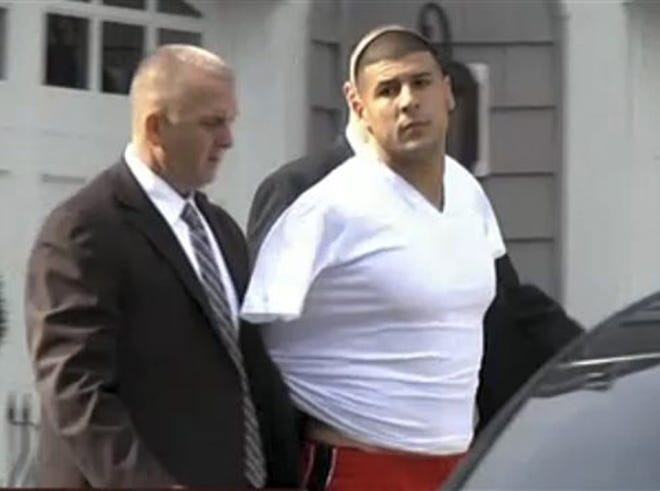 In this image taken from video, police escort Aaron Hernandez from his home in handcuffs in Attleboro, Mass., Wednesday, June 26, 2013. Hernandez was taken from his home more than a week after a Boston semi-pro football player was found dead in an industrial park a mile from Hernandez's house.