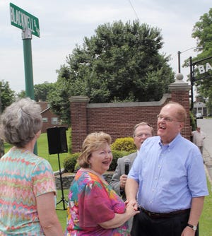 Dr. Michael Blackwell holds his wife Catherine's hand while admiring the new street sign named after him at Baptist Children's Homes of N.C.'s Mills Home Campus on Thursday.