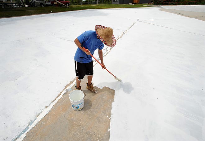 Painter Patrick Snow of Expressfit Liner in Hanson stays paints the Fino Field Memorial Pool in sweltering heat Wednesday. Snow was one of two employees using oversized hats for shade will working in the sweltering heat Wednesday. Weather permitting, the Milford Park Department plans to open the pool on Monday, July 1.