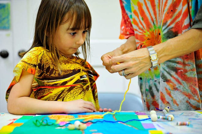 Instructor Ivey Coleman teaches Aaralyn Gagnon, 7, how to string her handmade beads during Coleman's fiber art class for 7- and 8-year-olds at the art institute.