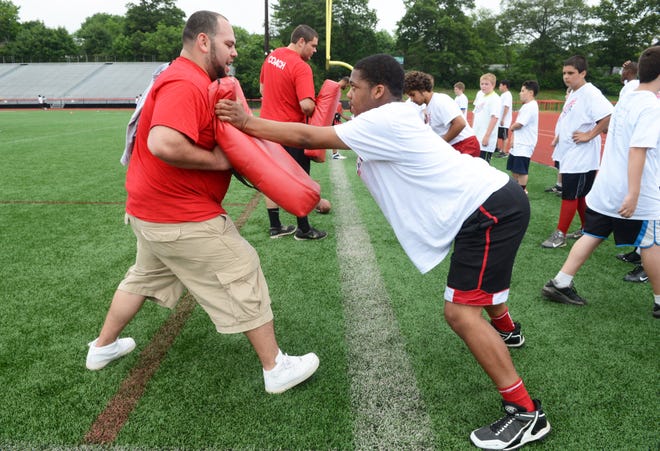 Coach Manny Garcia, left, works with Khoury Smith, 13, during blocking drills at the second annual Future Boxers Football Clinic at Marciano Stadium on Saturday.