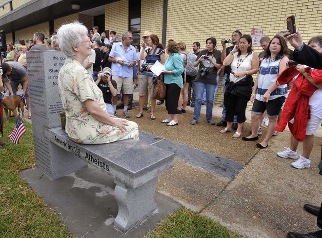 Will.Dickey@jacksonville.com Gael Murphy of Tampa sits on the newly unveiled atheist monument after a ceremony Saturday at the Bradford County Courthouse in Starke. The monument was erected near a monument for the Ten Commandments.