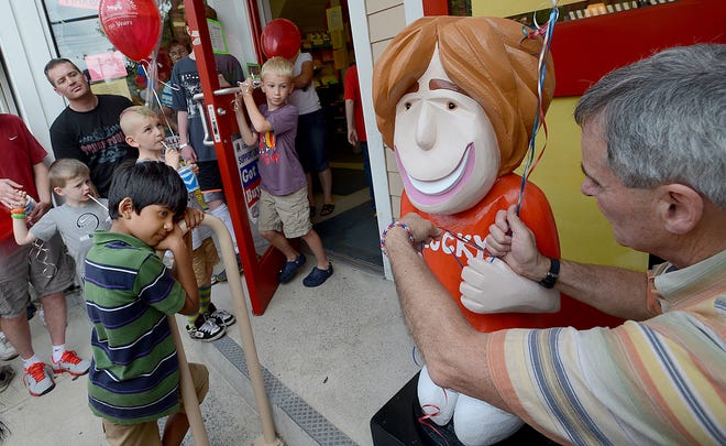 John Paltrineri, right, owner of Fiske's General Store in downtown Holliston, ties balloons to Lucky, his store's new mascot, during an unveiling ceremony Saturday. The store is known for recognizing birthdays and Paltrineri hopes that children will pat Lucky on the head and pose for a picture on their birthday.