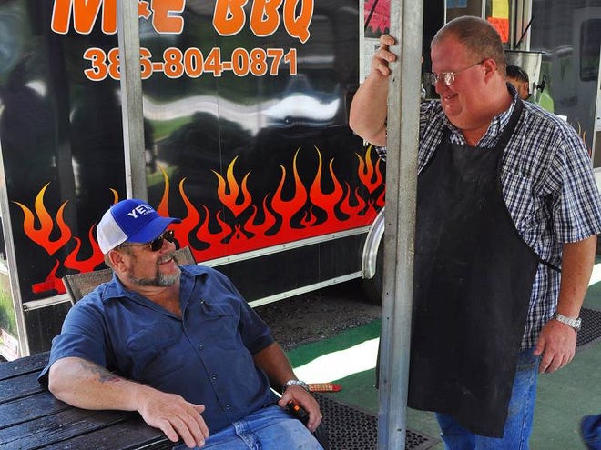 Mark Dubberly, sitting, and Eddie Braddock joke around at their roadside barbecue stand along North U.S. 17, in Pierson, on Wednesday afternoon.