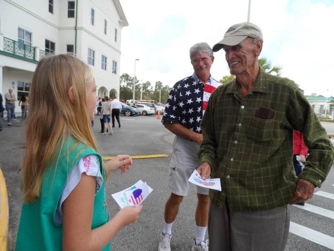 Girl Scout Abigail Lee, 9, gives cards recently to Army veterans George Haller, who served in World War II, and Dennis Chapman, who served in Vietnam. Membership in the Girl Scouts has been declining nationally and locally.