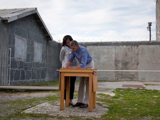 U.S. President Barack Obama, right, and first lady Michelle Obama write in a guest book after touring Robben Island, the historic Apartheid-era prison that held former South African president and anti-apartheid hero Nelson Mandela, Sunday, June 30, 2013, in Robben Island, South Africa. (AP Photo/Evan Vucci)