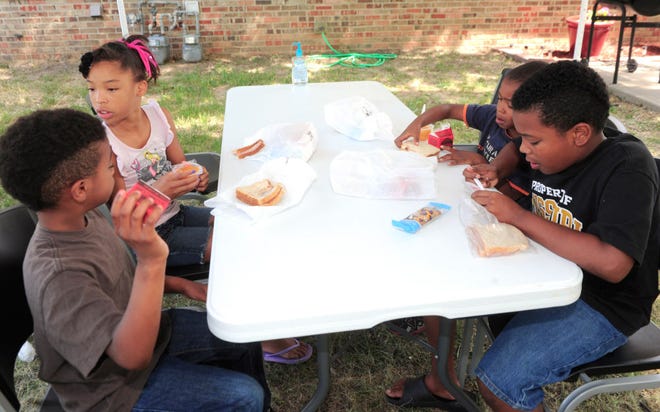 Clockwise from lower left, Tre McKee, 8, Ahmya McKee, 9, Cameron McKee, 6, and Markus Moore, 10, have lunch Tuesday at the Bear Creek housing development on Elleta Boulevard, one of four sites where the Food Bank for Central & Northeast Missouri provides meals for children.