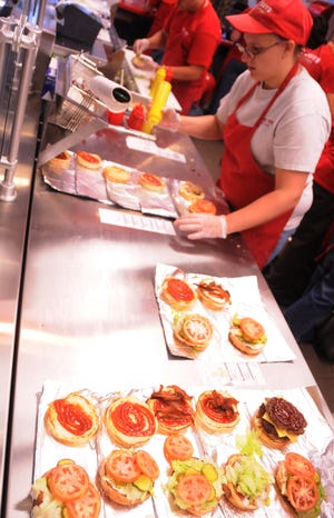 Employees at Five Guys makes hamburgers at Five Guys Tuesday afternoon on their second day in business.