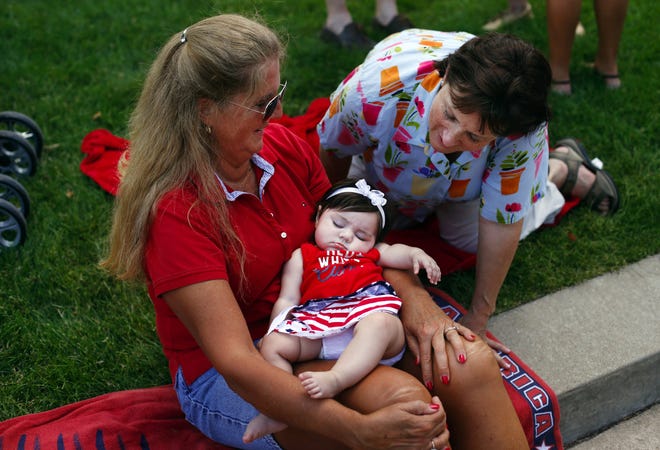 Vicki Hannah sneaks a peek at five-month-old Teagan Bensko as she naps in her grandma Paula Bensko's arms after collecting a handful of awards during a beauty pageant at the Capital City Celebration in downtown Springfield Thursday, July 4, 2013.