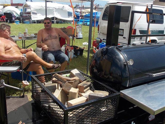 Richard Collins of Titusville and Duke Sarels of Rockledge relax under Sarels' dining fly in the infield at Daytona International Speedway on Saturday, July 6, 2013. They planned to smoke a turkey and bacon-wrapped Cornish hens later in the afternoon.