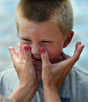 Ty Hollis, 5, of Berlin allows his mother, Jody, to apply sunblock to his face while on the beach at Hopkinton State Park.