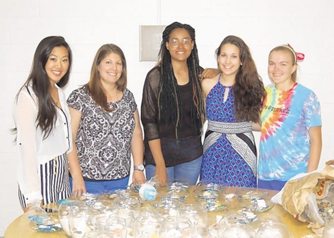 Newburgh Free Academy prom committee members, from left, Tiffany Lok, Jenna Carter-Johnson, Cassidy Mennerich and Hannah Flecksenstein, along with adviser Gina Scaduto, second from left, put the final touches on some of the 2013 NFA Senior Prom centerpieces.
