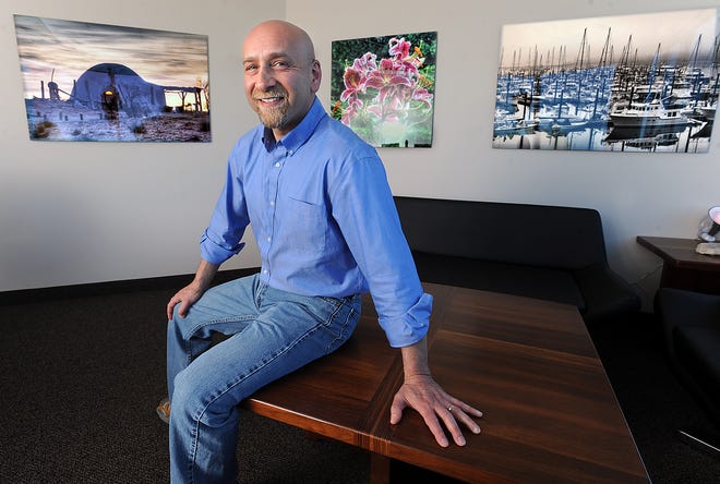 Rainier Communications CEO Stephen A. Schuster is seen in his Westborough office/gallery with his photographs.