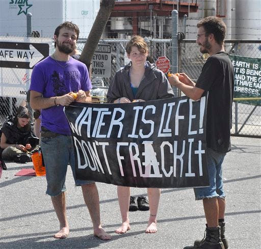 Protesters hold a banner during a protest outside of the Momentive resin plant, Monday, July 8, 2013, in Morganton, N.C. Dozens of environmental activists blocked a chemical plant Monday to protest against the company's sale of products used in the natural gas drilling process called hydraulic fracturing, or fracking. (AP Photo/The News Herald, Mary Elizabeth Robertson)