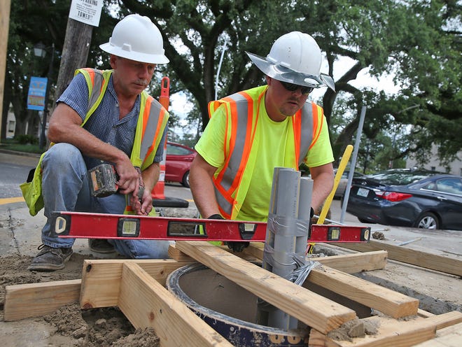 John McKensie (left) and Chris Pryor, of Jack Harper Electrical, work Tuesday on leveling a structure to house a control panel for a new decorative traffic light mast arm at the corner of Main and Church streets in Houma.
