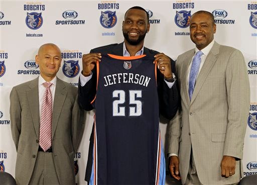 Charlotte Bobcats' Al Jefferson, center, holds up his jersey with Rod Higgins, right, president of basketball operations, and Rich Cho, left, general manager, during a news conference for the NBA basketball team in Charlotte, N.C., Wednesday, July 10, 2013. Jefferson, a free agent, signed with the Bobcats today. (AP Photo/Chuck Burton)