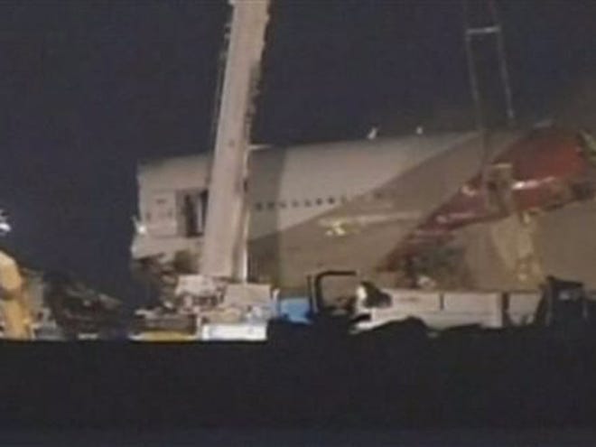 In this image from video provided by ABC7 News/KGO-TV a section of the fuselage of Asiana Flight-214 is removed at San Francisco airport early Friday morning July 12, 2013. Workers began clearing the wreckage early Friday. The Asiana flight crashed upon landing Saturday, July 6, at San Francisco International Airport, and two of the 307 passengers aboard were killed. (AP Photo/ABC7 News/KGO-TV)