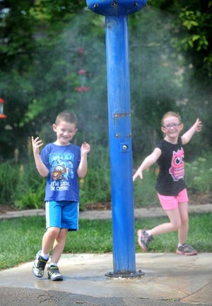 Carter Rhodes, 7, and Emma Rhodes, 8, cool off under the mist falls July 10 while visiting the Amarillo Zoo.