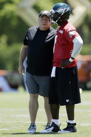 Eagles head coach Chip Kelly (left) talks with quarterback Michael Vick during Tuesday's minicamp workout at the NovaCare Complex.