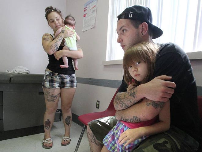 Chris Buzek holds his daugher, Alexis, 5, while mom, Sarah, holds 3-month-old Serenity at the Keech Street Clinic in Daytona Beach. Halifax Health operates the clinic for the indigent and is studying the new health care law.