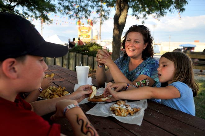 From left, Brandon Bennett, 12, his mother Laura and sister Ann, 7, of West Jersey Township enjoy funnel cake, elephant ears and ribbon fries on Sunday at the Heart of Illinois Fair.