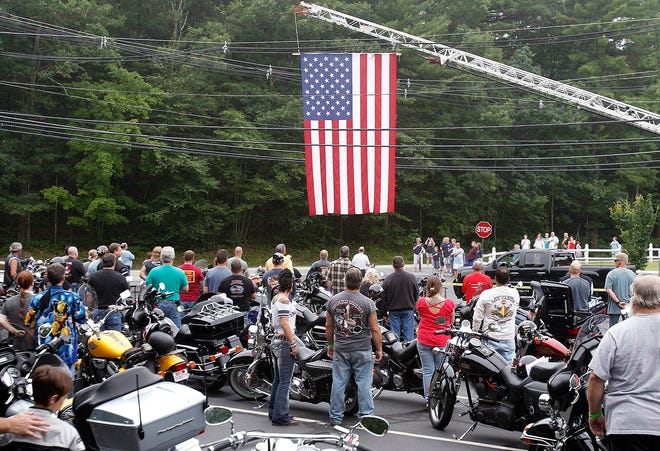 Motorcyclist and the crowd face the flag as the National Anthem is sung at the beginning of Saturday morning's Annual Thunder in the Valley motorcycle ride to honor Uxbridge Police Officer Chet Dzivasen at the VFW in Uxbridge.