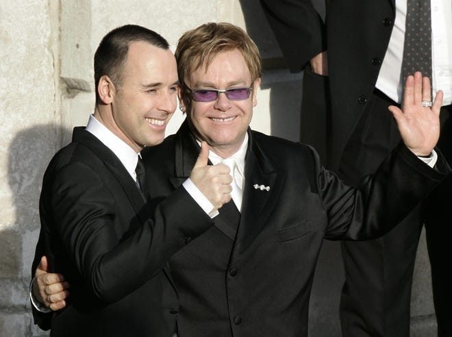 FILE - This is a Wednesday Dec. 21, 2005 file photo of pop star Elton John, right, and his longtime partner David Furnish, embrace as they wave to members of the media and the public after they had a civil ceremony at the Guildhall in the town of Windsor, England John and Furnish were the most prominent of hundreds of same-sex couples planning to form civil partnerships in England and Wales on Wednesday, the first day that such ceremonies become possible. With little fanfare or controversy, Britain announced Wednesday July 17, 2013 that Queen Elizabeth II _ hardly a social radical _ had signed into law a bill legalizing same-sex marriages in England and Wales. France has also legalized gay marriages, but only after a series of gigantic protests attracting families from the traditional heartland that revealed a deeply split society. (AP Photo/Lefteris Pitarakis)