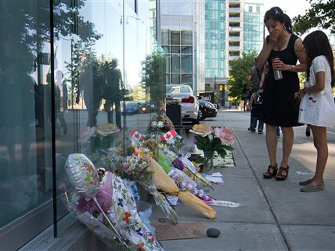 A woman reacts upon finding out Canadian actor Cory Monteith died as she pauses at a memorial for him outside the Fairmont Pacific Rim Hotel in Vancouver, B.C., on Monday July 15, 2013. Monteith's body was found in a room at the hotel Saturday. (AP Photo/The Canadian Press, Darryl Dyck)