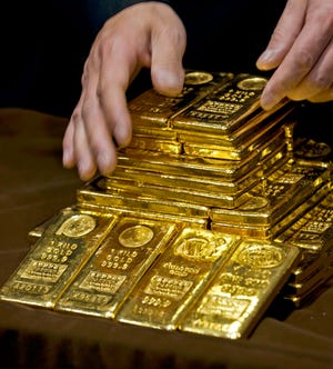 In an Oct. 17, 2011, file photo a staff member displays gold bullion bars during a news conference at the Chinese Gold and Silver Exchange Society in Hong Kong. A new study based on observations from space suggests the gold on Earth came from colliding dead stars in a cataclysmic event that occurred long ago. The research by the Harvard-Smithsonian Center for Astrophysics will appear in a future issue of the Astrophysical Journal Letters. (AP Photo, File)