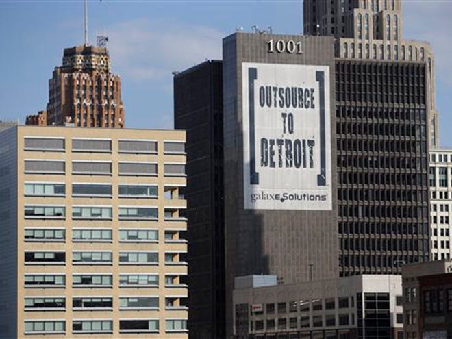 In this July 12 photo, an Outsource to Detroit banner from Galaxe.Solutions is seen on a Detroit building.