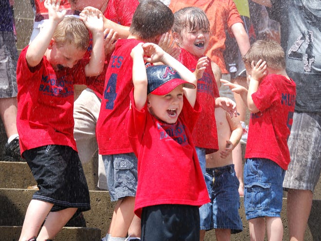 Kids react to getting sprayed with a water hose during a hot June game last year at McCormick Field.