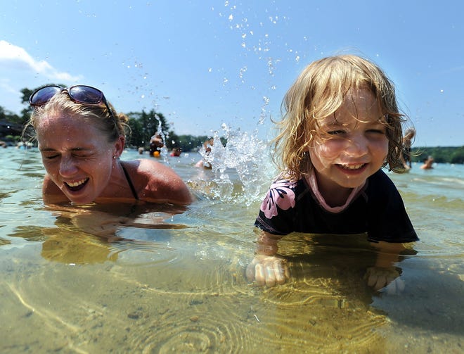 Shylah Maher, 2, of Hudson escapes the heat by splashing in the water with her mother, Kristen, at Marlborough's World War Two Memorial Beach.