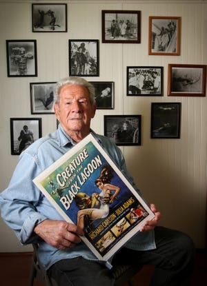 In this July 7, 2013 photo, Ricou Browning holds a poster from the movie "Creature from the Black Lagoon". In the mid 1950s, a grotesque costume turned Ricou Browning from a soft-spoken family man into an ugly “gill man,” also known as the “Creature from the Black Lagoon.” Now remembered along with King Kong and Godzilla as one of the most horrific monsters of the silver screen, Browning had the underwater role of the amphibious monster in Universal Studios' black-and-white horror flick, originally shot in 3-D. Browning then continued filling that role in two sequels, “Revenge of the Creature” and “The Creature Walks Among Us.” According to Browning, the underwater portions of the film were shot at Silver Springs, Wakulla Springs and in a tank at Marineland in St. Augustine. While professional actors played the creature on land, Browning donned the full-body suit for the underwater scenes.