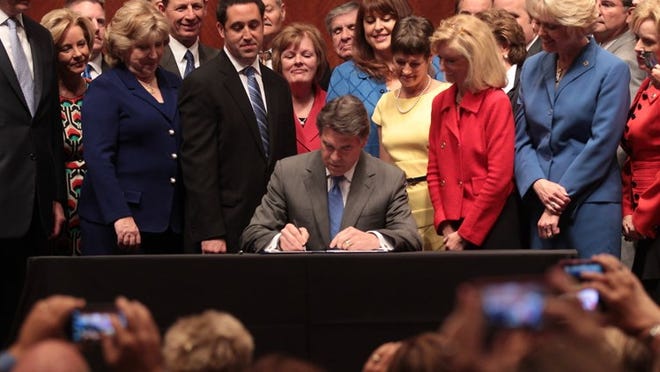 Gov. Rick Perry signed stricter abortion regulations into law Thursday morning as supporters cheered and faint chants of 'shame' intruded from protesters outside the Capitol auditorium.