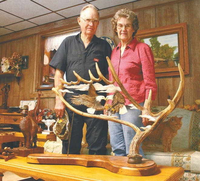 Bill and Shirley Swango, left, pose with a moose antler carving Bill made for their 54th wedding anniversary. The carving is composed of two eagles, seen bottom right. Bill also spent a week carving the angel's face (top right) and a week on the rest. He carves both his and Shirley's name into all of his pieces.
