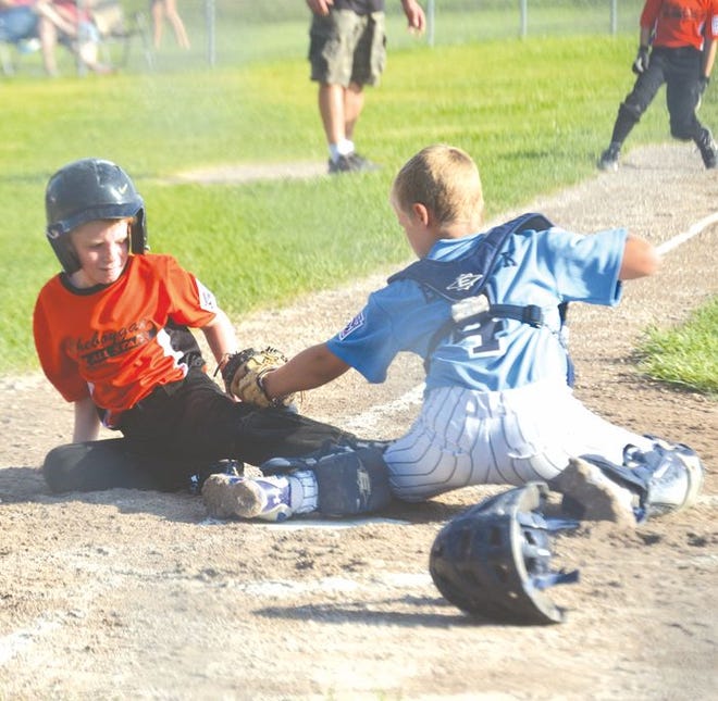 Cheboygan's Aidan Kosanke (left) scores a run, beating out a tag attempt from Petoskey's Tommy Budnick (right) during Friday's Minor Boys (9-10) District 13 championship game at Jim Elenbaas Field in Cheboygan.