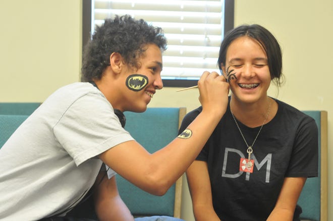Josh Williams, 17, paints a Mike Tyson face tattoo on Sabriana Velazquez, 16, during a face painting and hyena tattoo event as part of the Summer Reading Program by the San Bernardino County Library at the Newton T. Bass Library in Apple Valley on Wednesday, July 3rd.