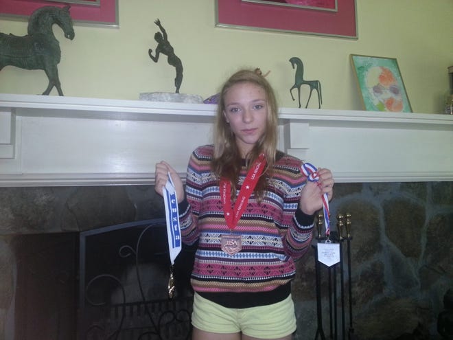 Miranda Gieg, 14, of Sudbury poses with some of her fencing medals.