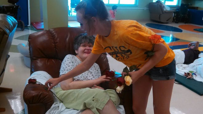 Canton High School cheerleader Sydney Simmons gives a rose to a nursing home resident at Renaissance Care Center Saturday. As a part of Hy-Vee's annual rose sale, cheerleaders from Canton High School delivered roses to nursing homes in Canton and around the rest of the Fulton County area.