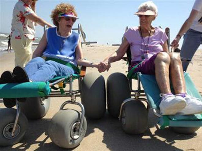 Barbara Casteen and a friend of hers from high school named Lois Mullinax, both 87, use beach wheelchairs at Fort Fisher in June.