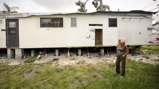 Bonnie Benamar looks at a dilapidated mobile home behind hers in Lago Palma in Lake Worth Thursday, July 18, 2013. "It was beautiful when I moved in," she said. "I was content, and it was nice. The new owner raised rent and there's been a boil water notice for over a month. They started moving in run-down mobile homes in the middle of hurricane season. Code enforcement was here a week ago and put out 15 warnings. The head of maintenance took them all off. They just don't care. It has turned into a nightmare." Benamar said that the dilapidated mobile homes were bringing in "all kinds of bugs and roaches." (Bruce R. Bennett/The Palm Beach Post)