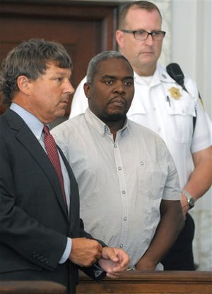 Ernest Wallace, of Miramar, Fla., center, stands next to his attorney David Meier, left, and a court officer, right, in Attleboro District Court, in Attleboro, Mass., during his arraignment, Monday, July 8, 2013. Wallace is facing an accessory to murder charge in the case involving former New England Patriots tight end Aaron Hernandez and has been ordered held without bail.