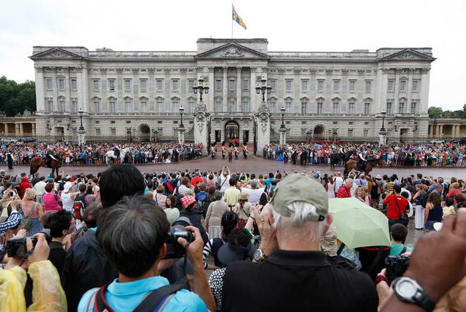 People watch the Changing of the Guard as a notice proclaiming the birth of a baby boy of Prince William and Kate, Duchess of Cambridge is put on display for the public view at Buckingham Palace in London, Tuesday, July 23, 2013. It's Day One of parenting for Prince William and Kate. After the excitement and fatigue and joy of childbirth - emotions shared with a nation - the young couple is expected to bring the prince home Tuesday. It is a daunting moment for any young couple, even one with as much support as the Duke and Duchess of Cambridge. (AP Photo/Sang Tan)