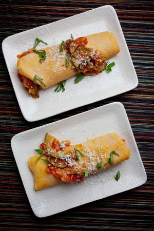 Local summertime vegetables are included in a ratatouille that is then rolled inside crepes. The crepes are topped with cheese before serving.