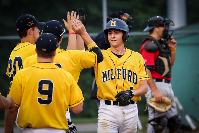 Milford Post 59's Brendan Pounds (right) is high-fived by teammates after scoring during Game 1 of the Zone 4 tournament against Grafton Hill Post 323 at Fino Field in Milford on Monday evening.