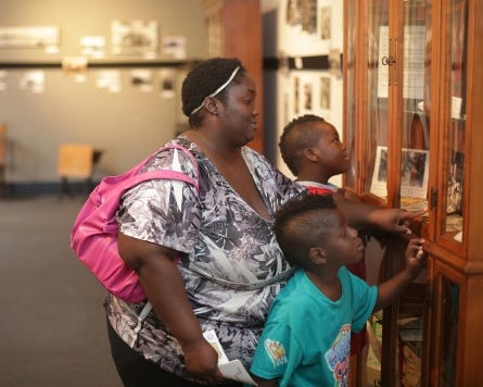Tanisha Philyaw checks out the centennial display with her sons, 6-year-old Joshua Tyler, foreground, and 9-year-old Jeremiah Stovall at the Visual Arts Center in Panama City. The timeline of Bay County’s history stretches around the room.